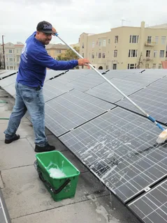 Technician cleaning solar panels on a rooftop in Gold Coast